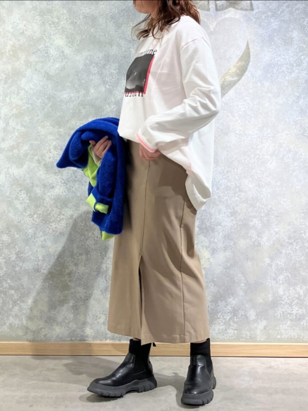 ベージュ系のスカート、ブルー系のカーディガン/ボレロ、ホワイト系のTシャツ/カットソーを着用したレディースの秋コーディネートの2枚目の写真