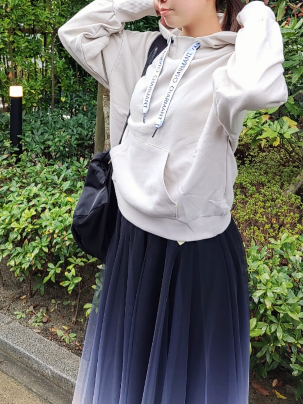 ブラック系のスカート、ベージュ系のパーカー、ホワイト系のスニーカーを着用したレディースの秋コーディネートの3枚目の写真