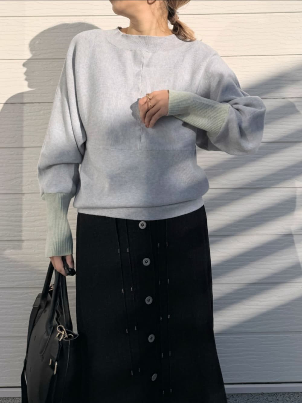 ブラック系のデニムスカート、ブラック系のトートバッグ、グレー系のニット/セーターを着用したレディースの冬コーディネートの3枚目の写真