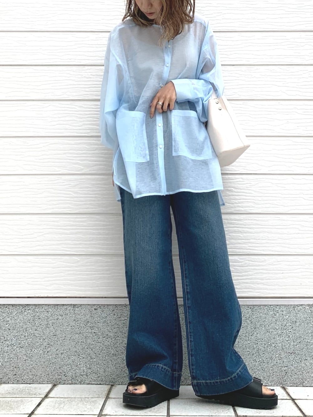 ブルー系のデニムパンツ、ブラック系のサンダル、ホワイト系のハンドバッグを着用したレディースの春コーディネートの2枚目の写真