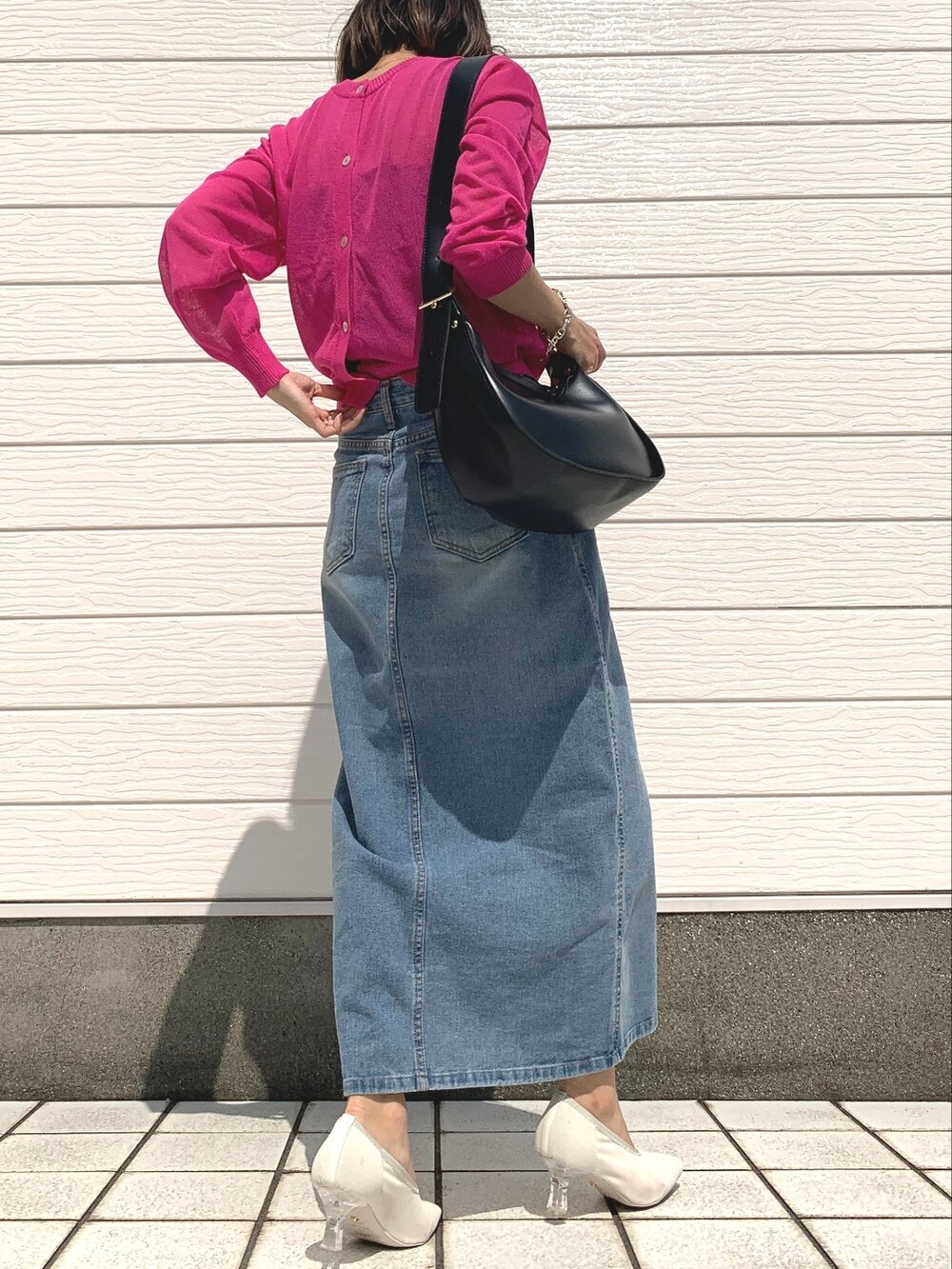 ブルー系のデニムスカート、ピンク系のカーディガン/ボレロ、ブラック系のショルダーバッグを着用したレディースの春コーディネートの2枚目の写真