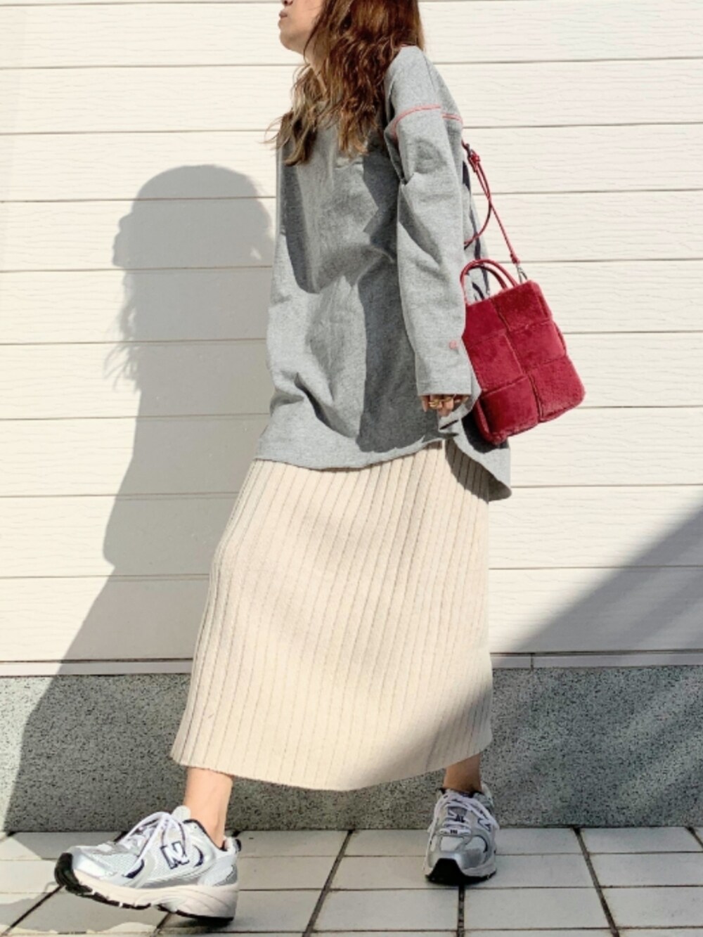 ホワイト系のスカート、シルバー系のスニーカー、グレー系のTシャツ/カットソーを着用したレディースの秋コーディネートの2枚目の写真