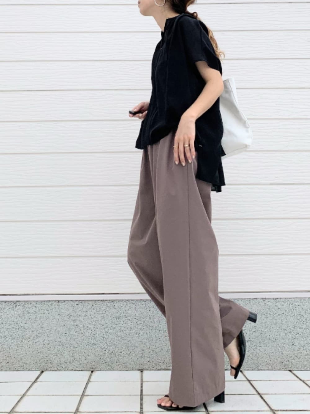 ホワイト系のトートバッグ、ブラウン系のその他パンツ、ブラック系のシャツ/ブラウスを着用したレディースの夏コーディネートの2枚目の写真