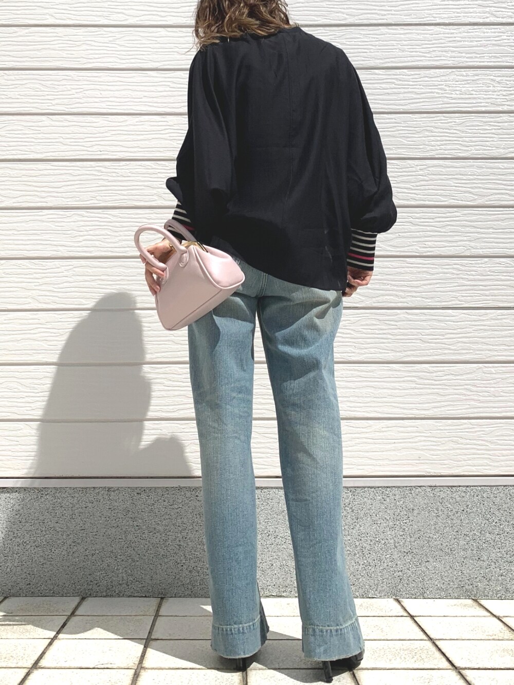 ブルー系のデニムパンツ、ピンク系のショルダーバッグ、ブラック系のシャツ/ブラウスを着用したレディースの春コーディネートの2枚目の写真