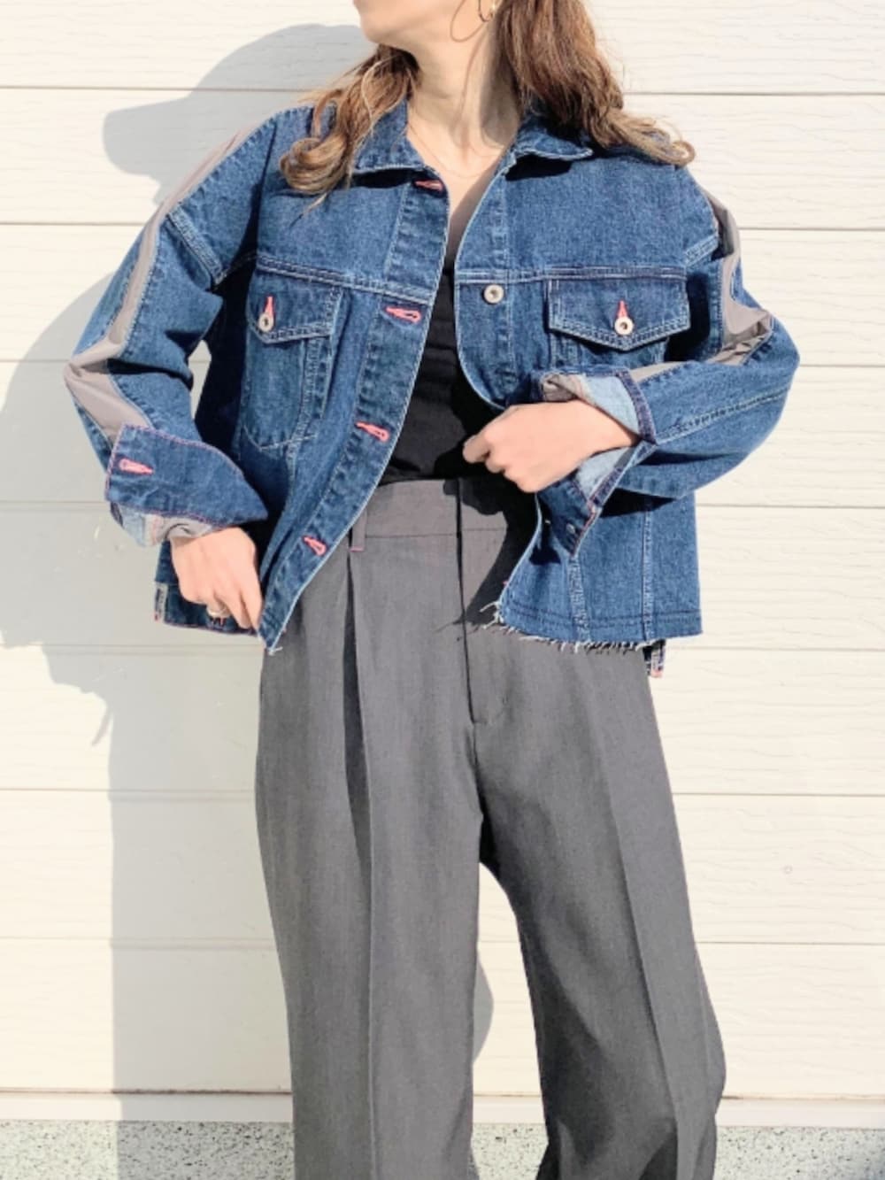 グレー系のスラックス、ブルー系のデニムジャケット、ブラック系のキャミソールを着用したレディースの冬コーディネートの3枚目の写真