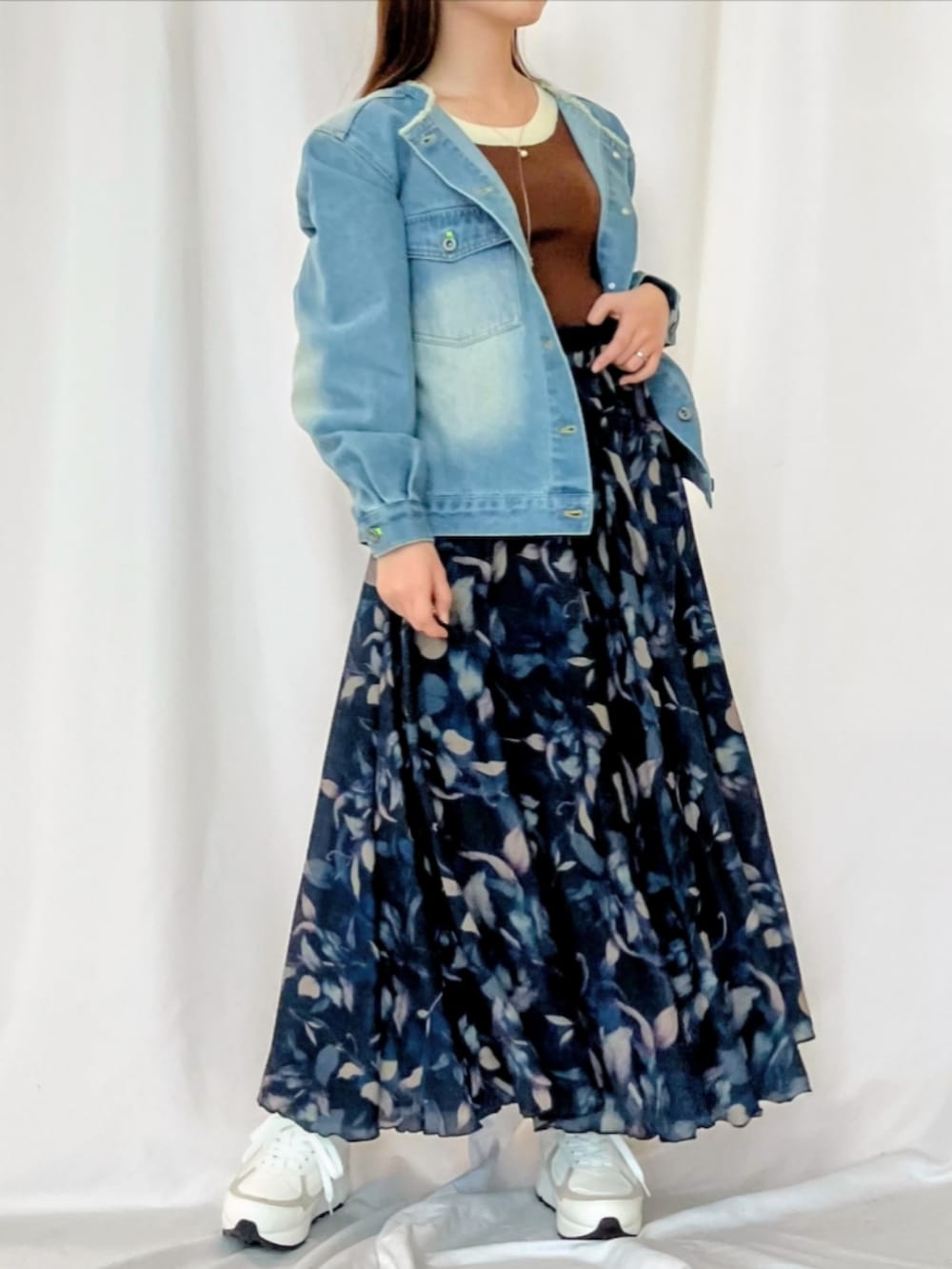 ブルー系のスカート、ホワイト系のスニーカー、ブルー系のデニムジャケットを着用したレディースの冬コーディネートの2枚目の写真