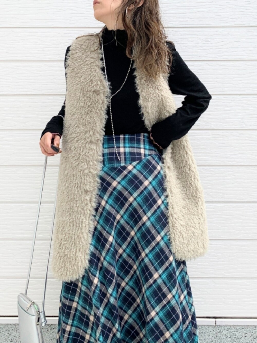 ベージュ系のベスト、シルバー系のショルダーバッグ、ブルー系のスカートを着用したレディースの秋コーディネートの4枚目の写真