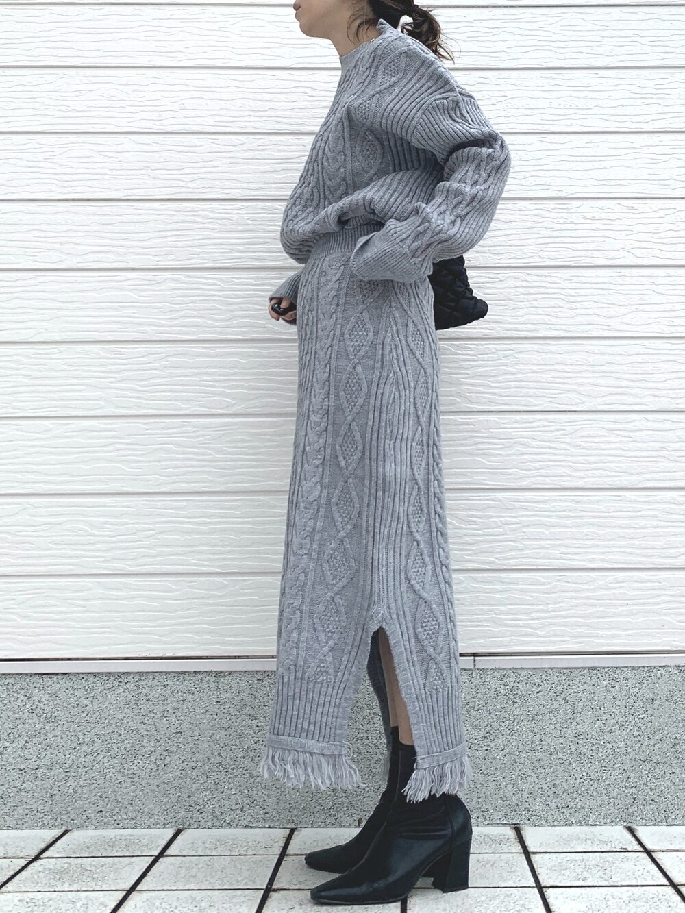 ブラック系のショルダーバッグ、グレー系のスカート、グレー系のニット/セーターを着用したレディースの冬コーディネートの2枚目の写真