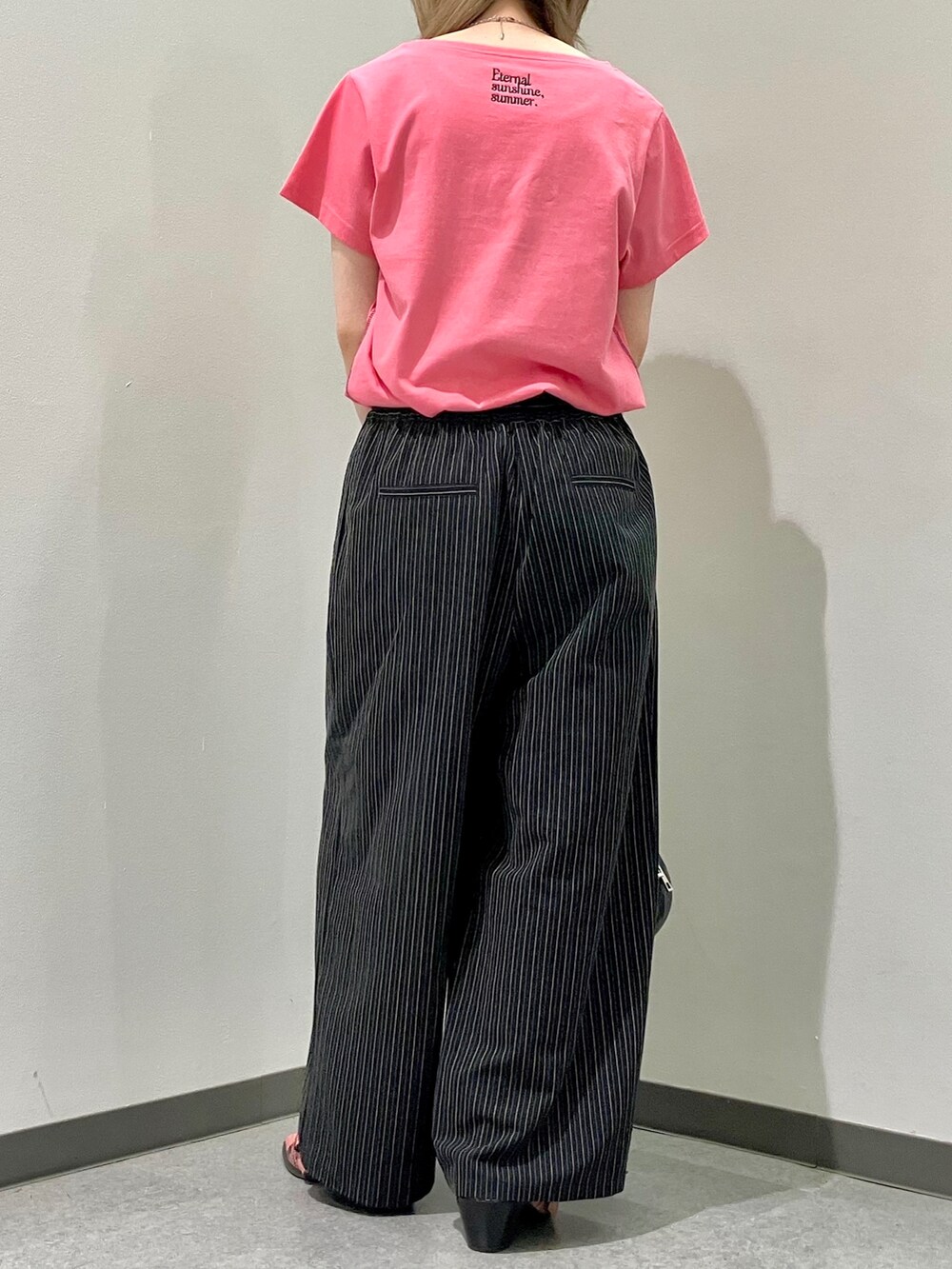 ピンク系のTシャツ/カットソー、ブラック系のスラックス、ブラック系のボストンバッグを着用したレディースの夏コーディネートの3枚目の写真