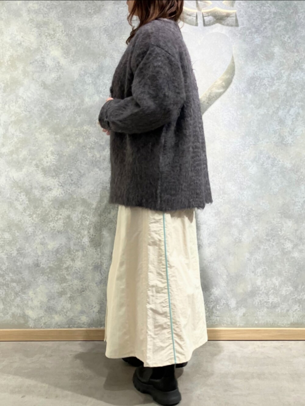 ブラウン系のカーディガン/ボレロ、ホワイト系のニット/セーター、ホワイト系のデニムスカートを着用したレディースの冬コーディネートの2枚目の写真