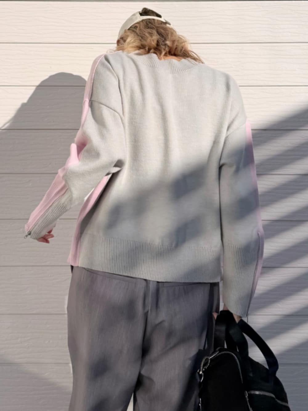 ホワイト系のスニーカー、グレー系のスラックス、ピンク系のニット/セーターを着用したレディースの冬コーディネートの5枚目の写真