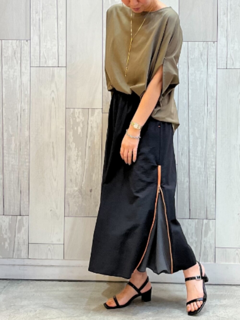 グリーン系のTシャツ/カットソー、ブラック系のスカートを着用したレディースの夏コーディネートの2枚目の写真