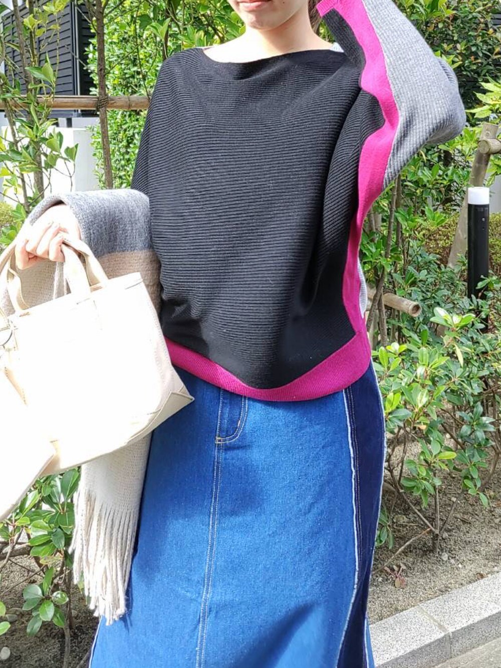 ベージュ系のトートバッグ、ブラック系のニット/セーター、ブラック系のスニーカーを着用したレディースの秋コーディネートの4枚目の写真