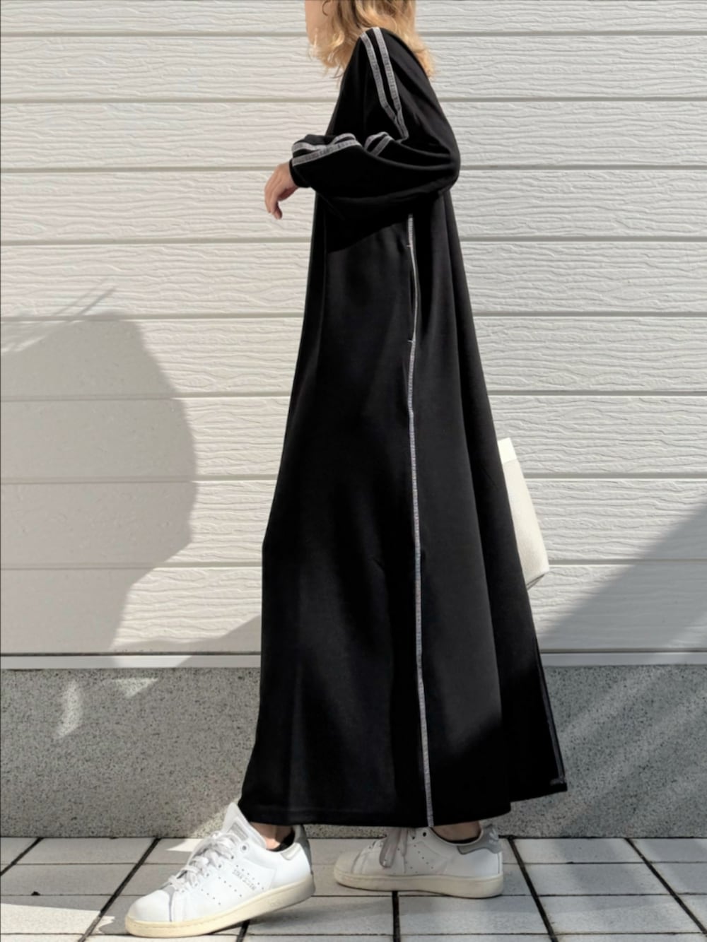 ホワイト系のスニーカー、ブラック系のワンピース、グレー系のトートバッグを着用したレディースの秋コーディネートの2枚目の写真