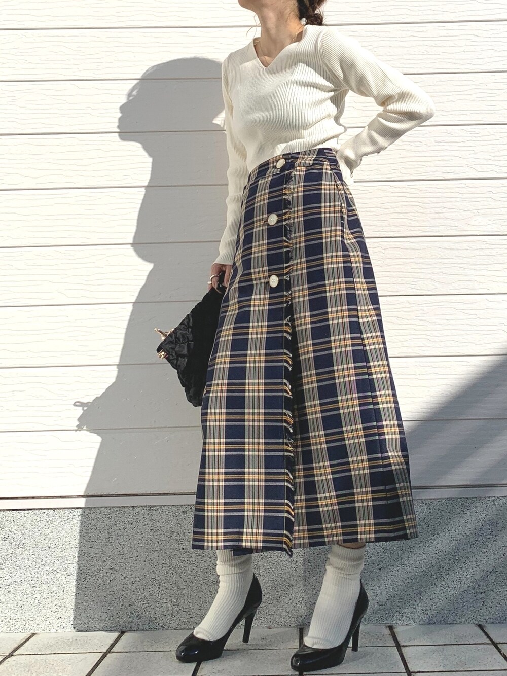 ブルー系のスカート、ブラック系のショルダーバッグ、ホワイト系のニット/セーターを着用したレディースの秋コーディネートの3枚目の写真