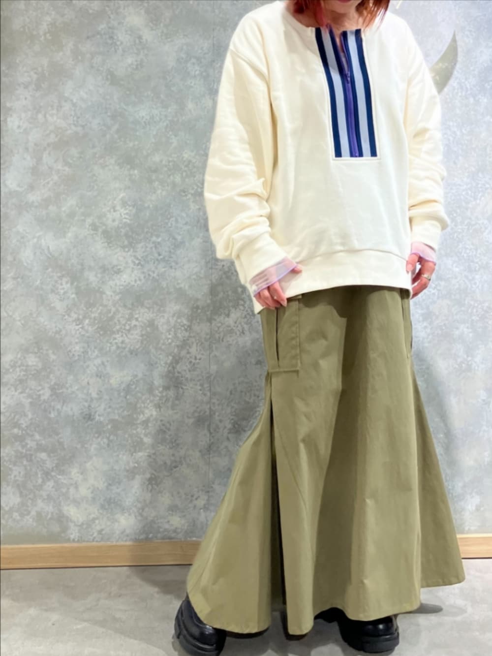 グリーン系のスカート、ホワイト系のスウェット、ホワイト系のブーツを着用したレディースの秋コーディネートの2枚目の写真