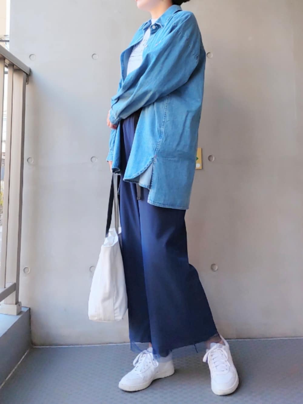 ホワイト系のトートバッグ、ホワイト系のスニーカー、ブルー系のシャツ/ブラウスを着用したレディースの冬コーディネートの3枚目の写真