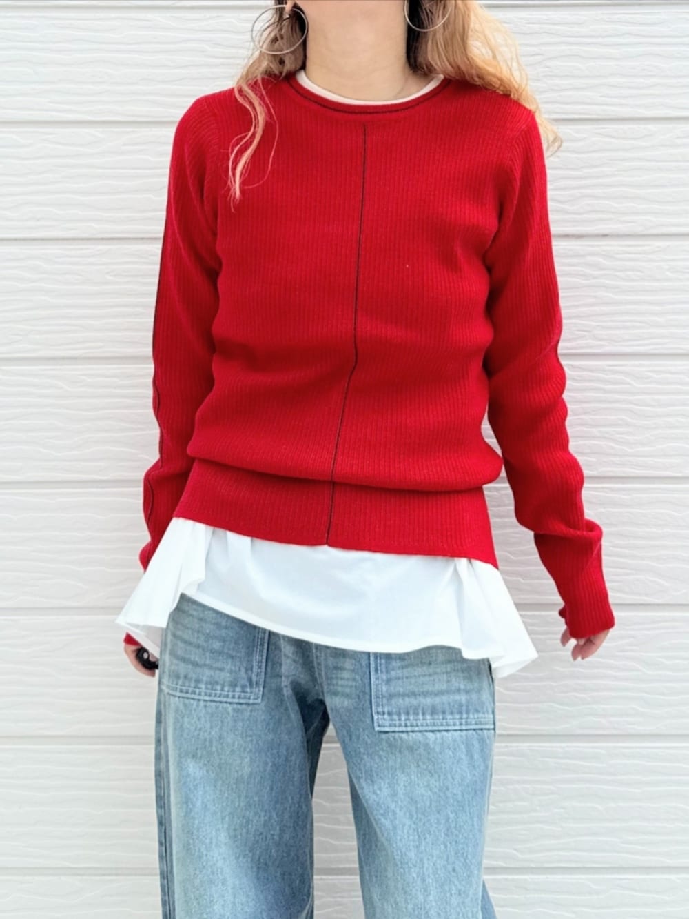 レッド系のニット/セーター、ブルー系のデニムパンツ、ホワイト系のTシャツ/カットソーを着用したレディースの秋コーディネートの4枚目の写真