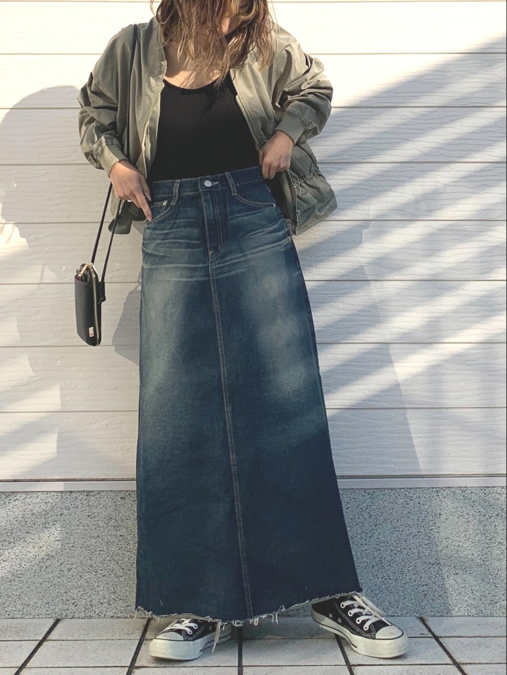 ブラック系のキャミソール、ブルー系のデニムスカート、ブラック系のスニーカーを着用したレディースの冬コーディネートの4枚目の写真