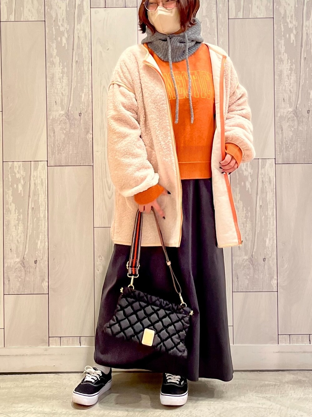 ブラック系のショルダーバッグ、グレー系のスカート、オレンジ系のニット/セーターを着用したレディースの秋コーディネートの2枚目の写真