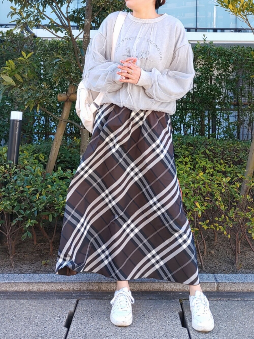 ホワイト系のバックパック/リュック、ブラウン系のスカート、ホワイト系のスニーカーを着用したレディースの秋コーディネートの3枚目の写真