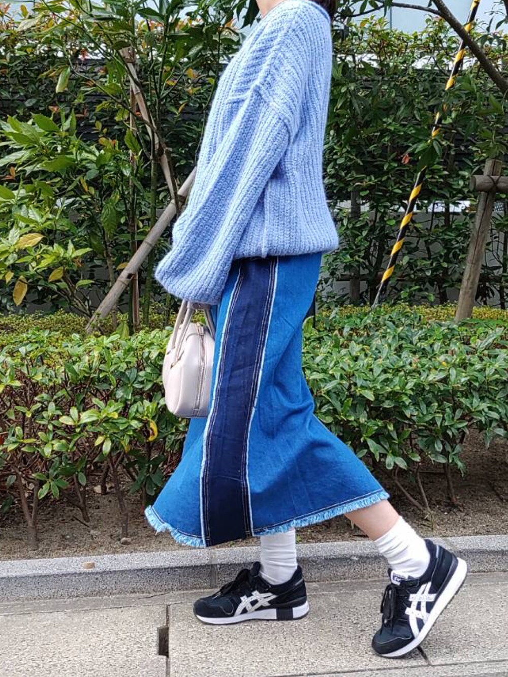 ブルー系のニット/セーター、ブルー系のデニムスカート、ホワイト系のボストンバッグを着用したレディースの秋コーディネートの2枚目の写真