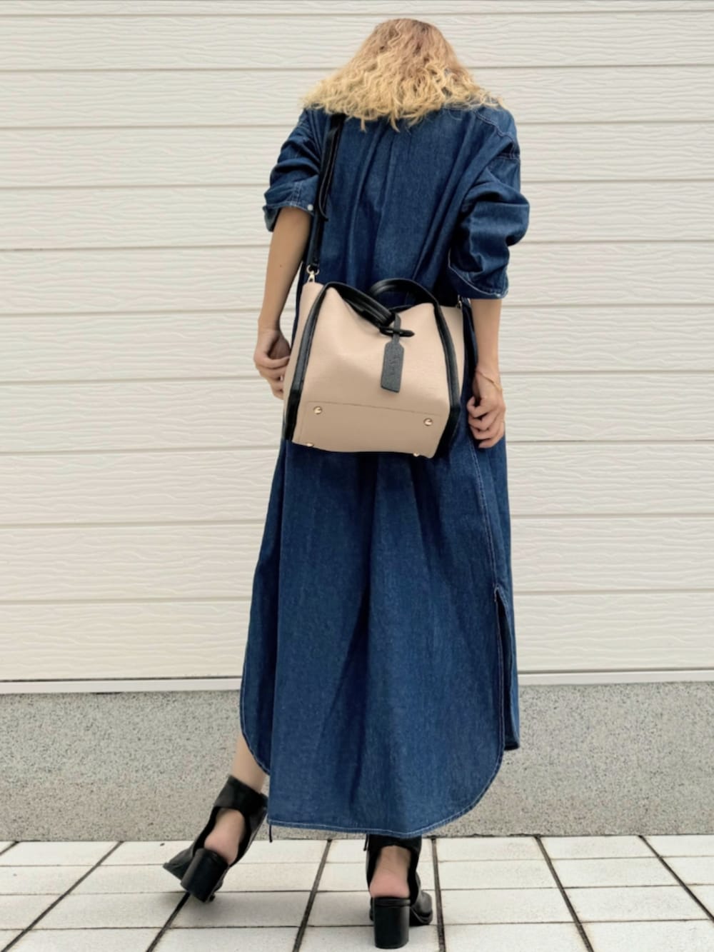 ブラック系のサンダル、ブルー系のシャツワンピース、ベージュ系のハンドバッグを着用したレディースの夏コーディネートの4枚目の写真