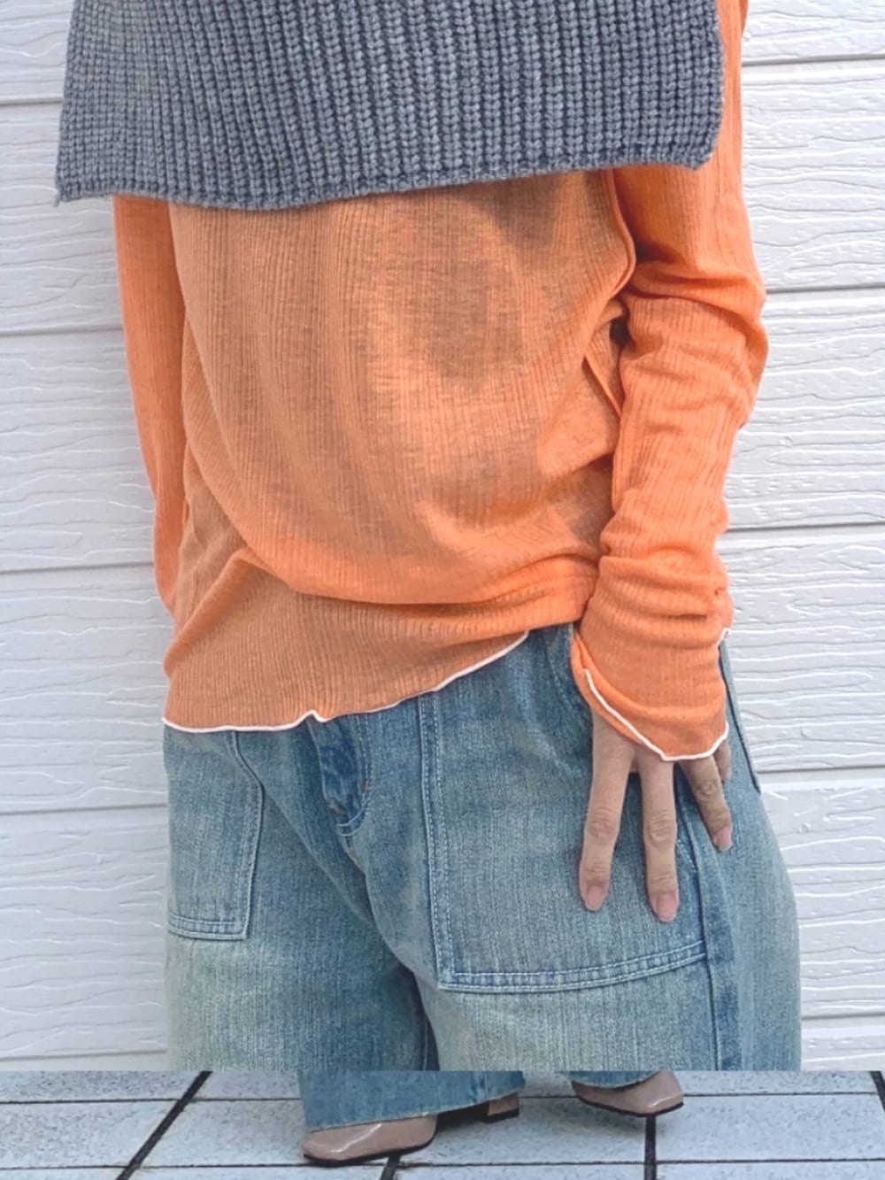 オレンジ系のTシャツ/カットソー、ブルー系のデニムパンツ、グレー系のネックウォーマー/スヌードを着用したレディースの冬コーディネートの3枚目の写真