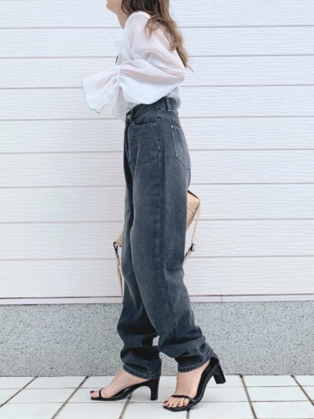 ホワイト系のシャツ/ブラウス、ベージュ系のクラッチバッグ、グレー系のデニムパンツを着用したレディースの春コーディネートの2枚目の写真