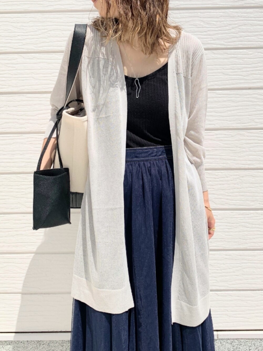 ブラック系のハンドバッグ、ブルー系のスカート、グレー系のカーディガン/ボレロを着用したレディースの春コーディネートの3枚目の写真