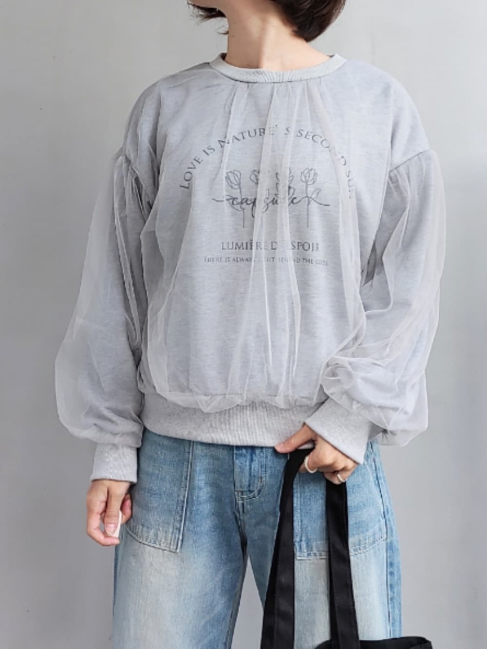 ブルー系のデニムパンツ、ブラック系のトートバッグ、グレー系のスウェットを着用したレディースの秋コーディネートの3枚目の写真