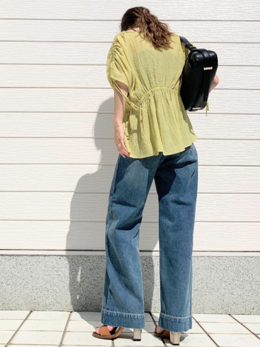 ブラック系のショルダーバッグ、ブラウン系のサンダル、イエロー系のシャツ/ブラウスを着用したレディースの春コーディネートの3枚目の写真