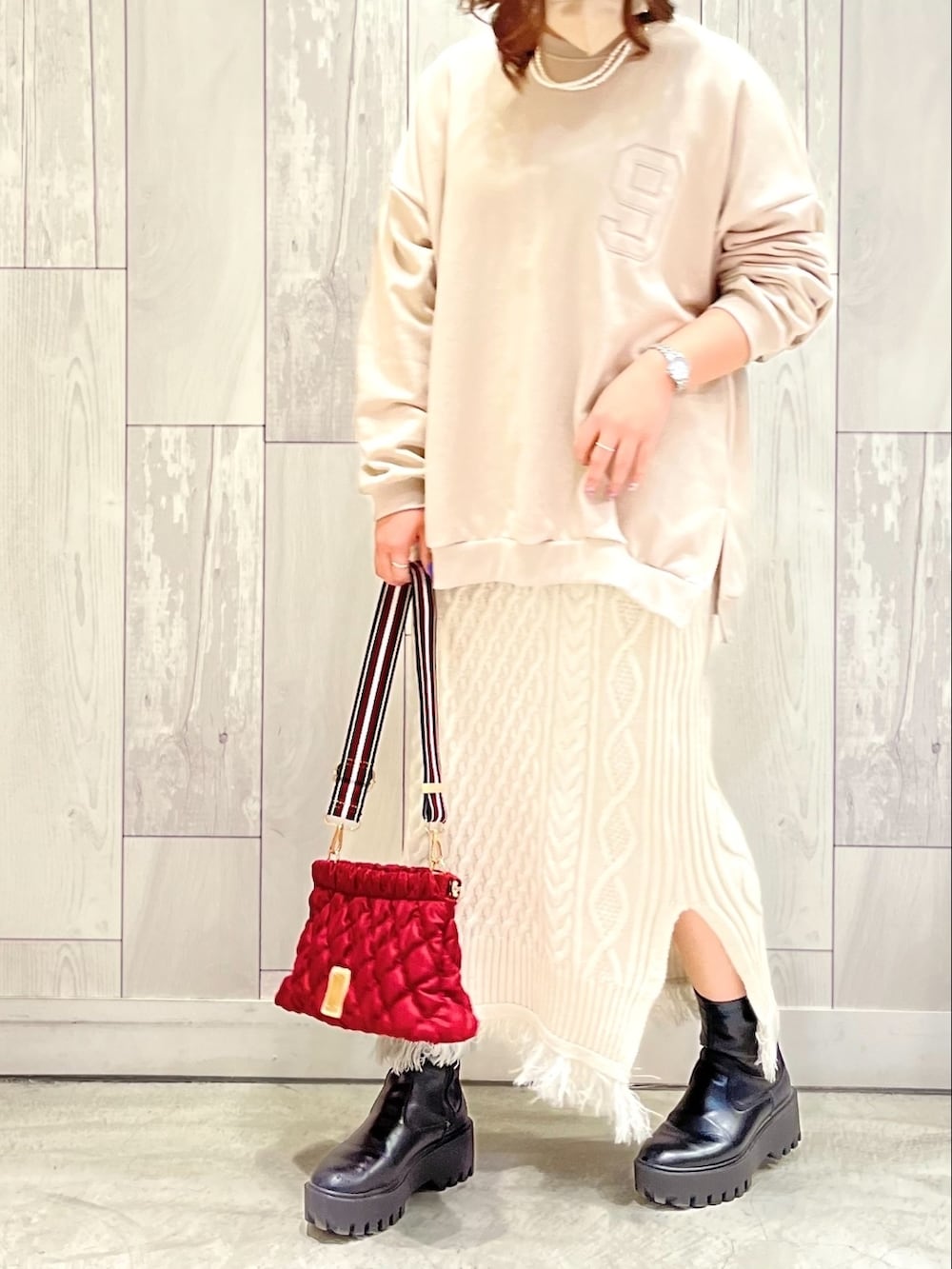 ベージュ系のスウェット、ホワイト系のスカート、レッド系のショルダーバッグを着用したレディースの冬コーディネートの2枚目の写真