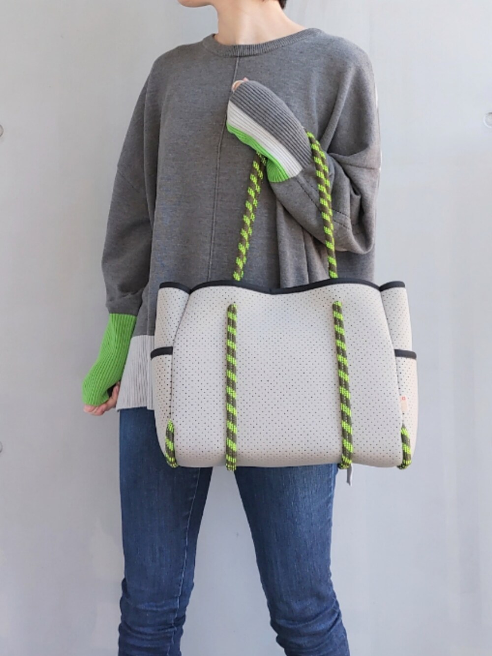 グレー系のトートバッグ、ブルー系のデニムパンツ、グレー系のニット/セーターを着用したレディースの冬コーディネートの4枚目の写真