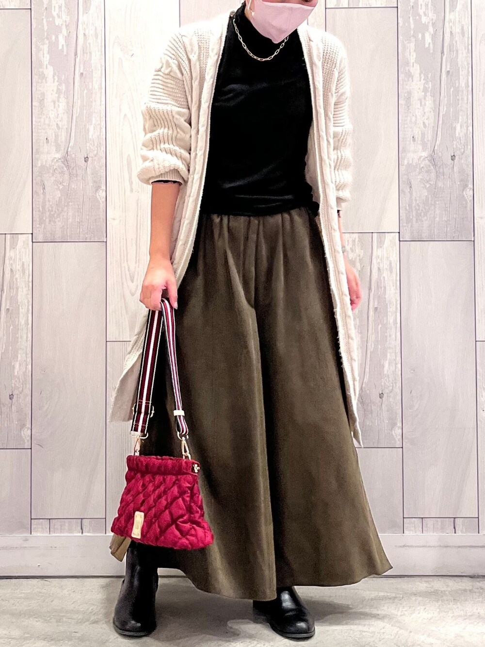 レッド系のショルダーバッグ、グリーン系のスカート、ブラック系のTシャツ/カットソーを着用したレディースの冬コーディネートの2枚目の写真
