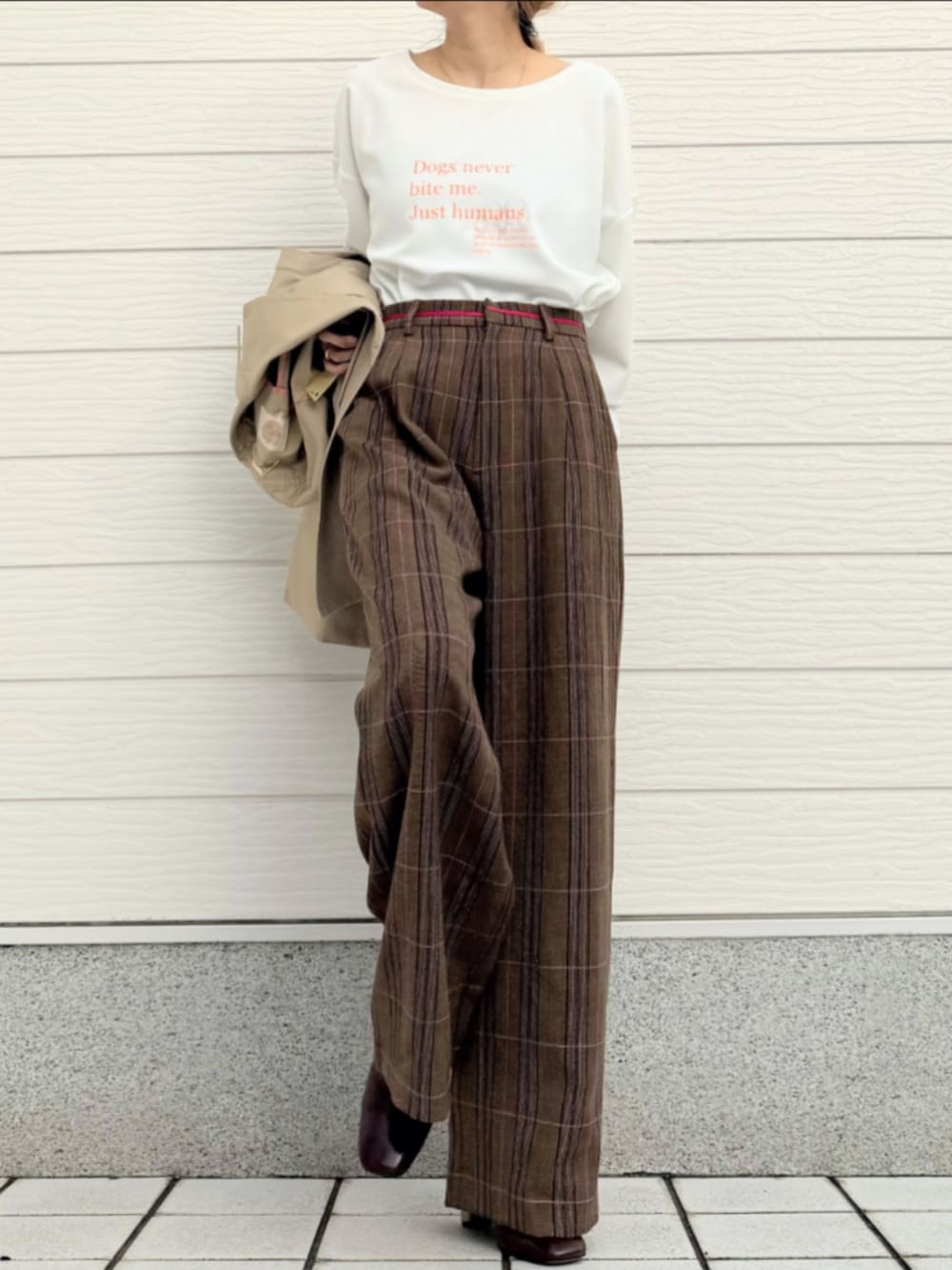 ホワイト系のTシャツ/カットソー、ベージュ系のトレンチコート、ブラウン系のスラックスを着用したレディースの冬コーディネートの2枚目の写真