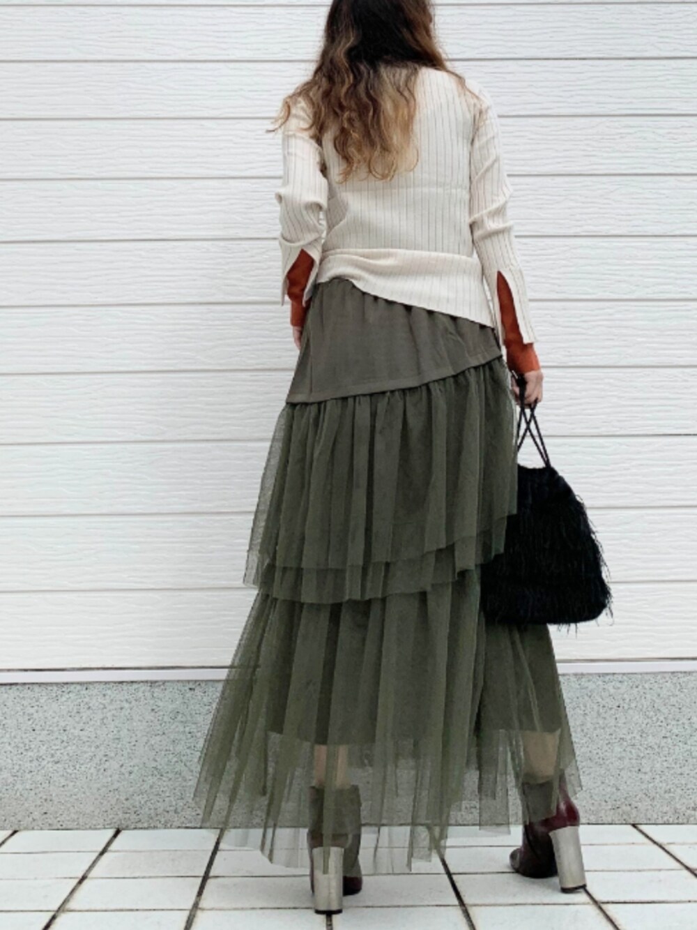 ブラウン系のブーツ、ホワイト系のニット/セーター、ブラック系のクラッチバッグを着用したレディースの秋コーディネートの3枚目の写真