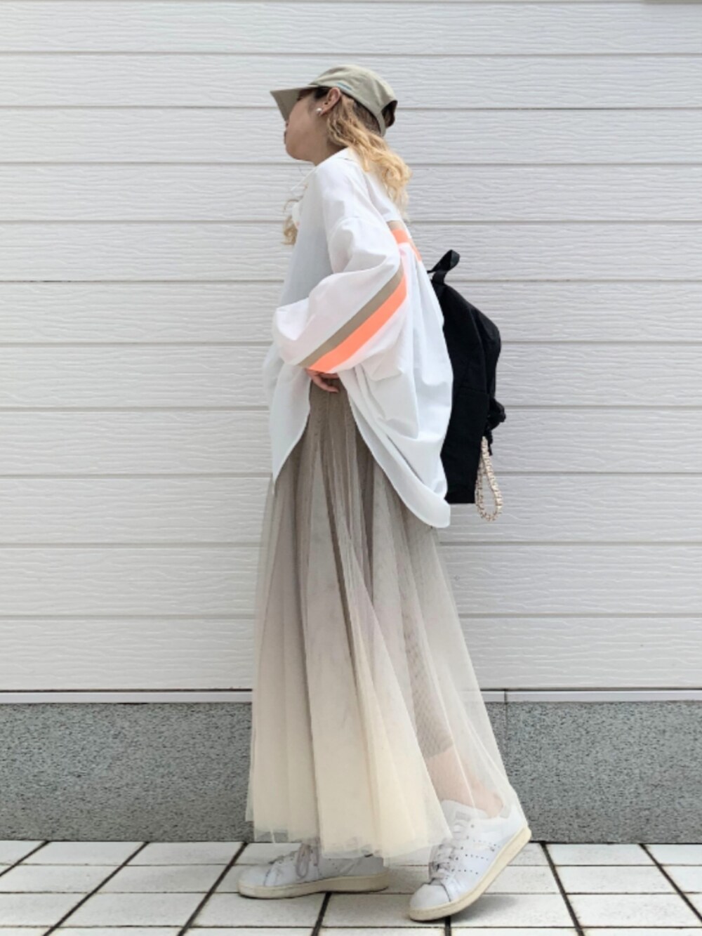 ゴールド系のスカート、ホワイト系のスニーカー、ブラック系のバックパック/リュックを着用したレディースの夏コーディネートの2枚目の写真