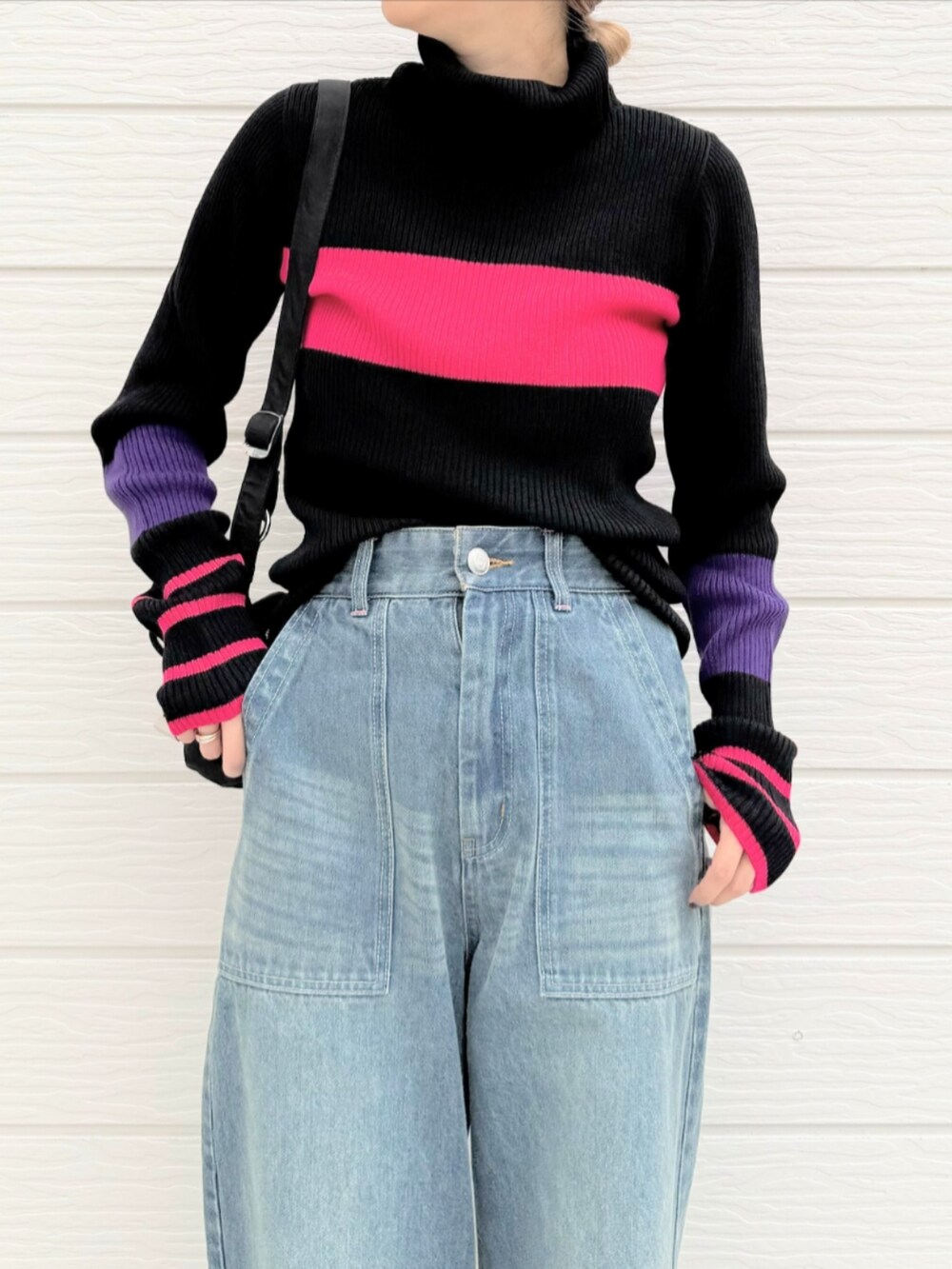 ブルー系のデニムパンツ、ブラック系のショルダーバッグ、ブラック系のスニーカーを着用したレディースの秋コーディネートの3枚目の写真