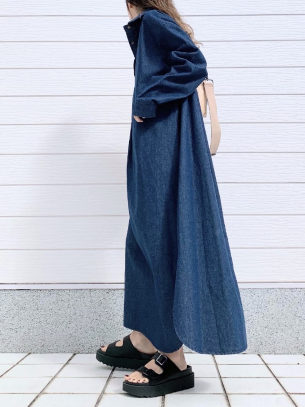 ブラック系のサンダル、ブルー系のシャツワンピース、ベージュ系のクラッチバッグを着用したレディースの春コーディネートの2枚目の写真