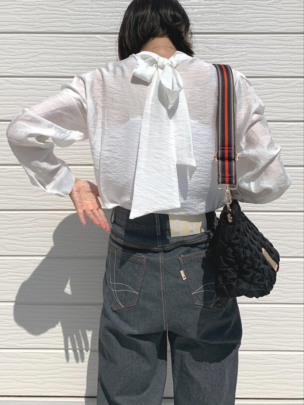 グレー系のデニムパンツ、ブラック系のショルダーバッグ、ホワイト系のシャツ/ブラウスを着用したレディースの夏コーディネートの3枚目の写真