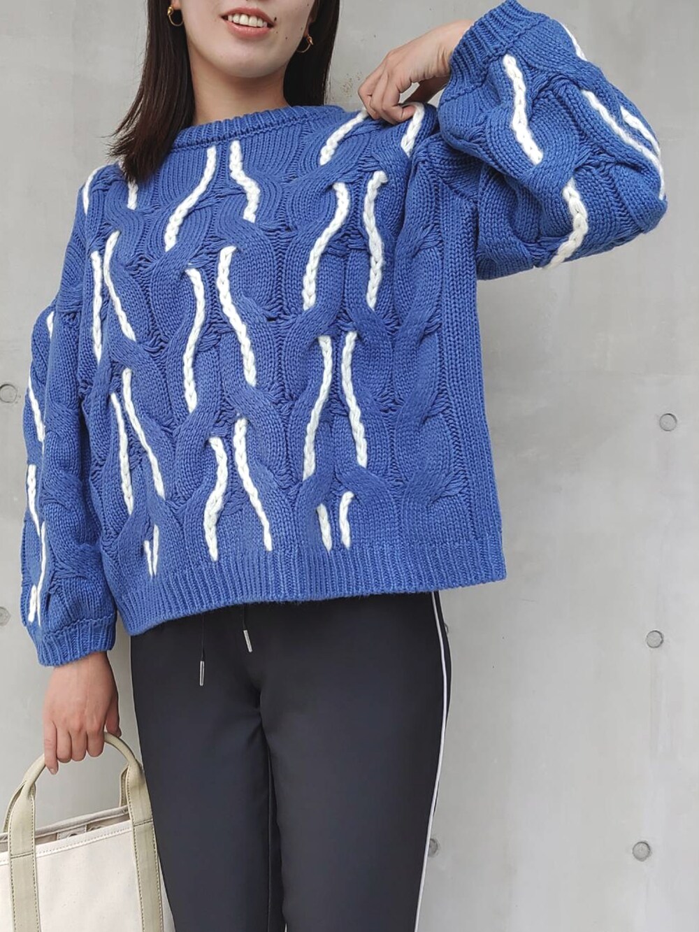 ブラック系のその他パンツ、ブルー系のニット/セーター、ベージュ系のトートバッグを着用したレディースの秋コーディネートの5枚目の写真