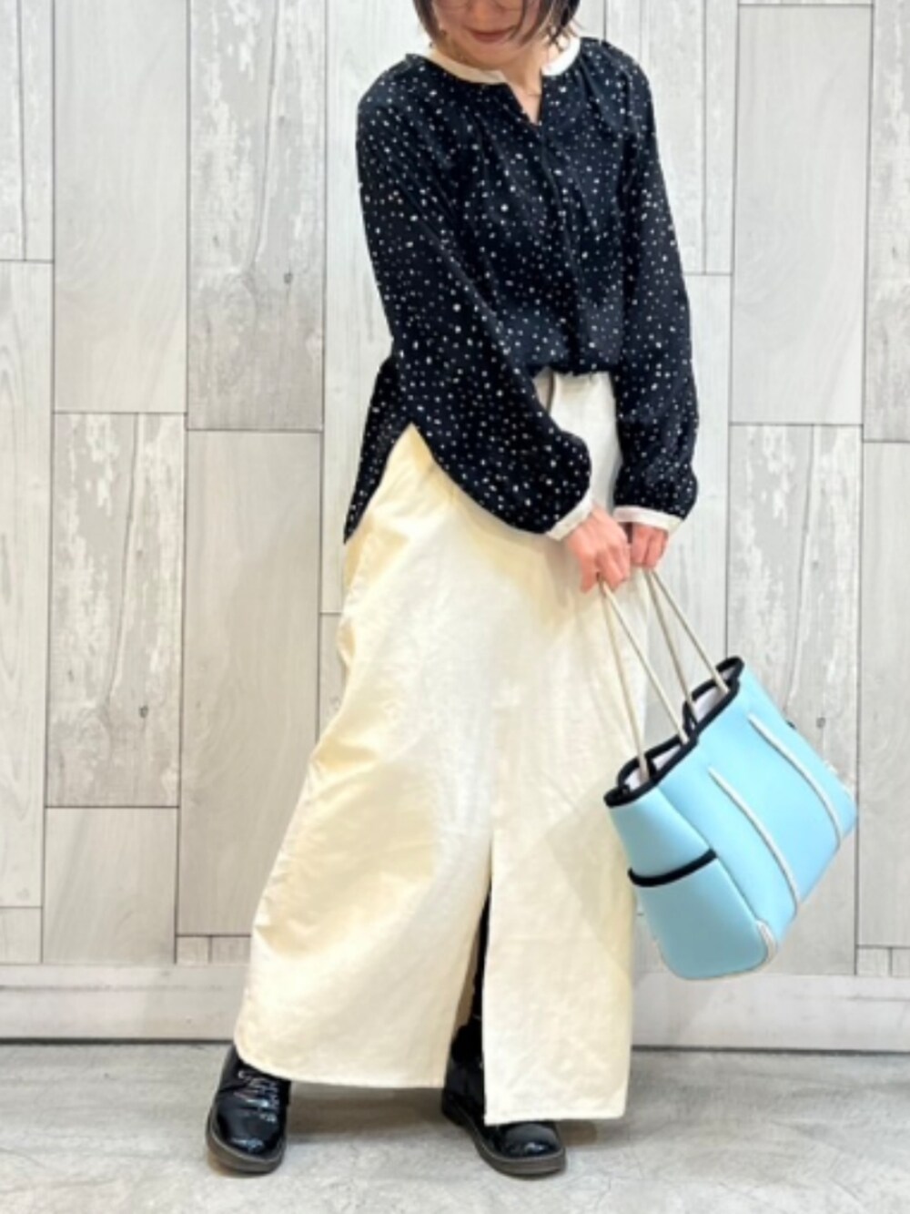 ブルー系のトートバッグ、ブラック系のシャツ/ブラウス、ホワイト系のデニムスカートを着用したレディースの冬コーディネートの2枚目の写真