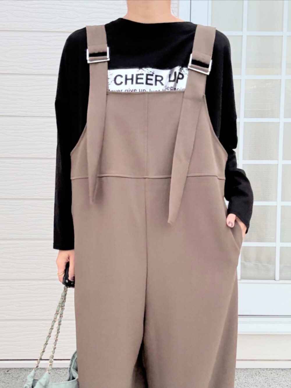 グリーン系のトートバッグ、ブラック系のTシャツ/カットソー、ブラウン系のブーツを着用したレディースの秋コーディネートの4枚目の写真