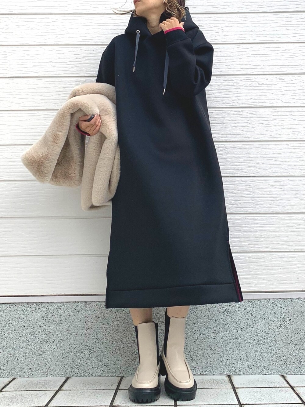 ベージュ系のベスト、ホワイト系のブーツ、ブラック系のワンピースを着用したレディースの秋コーディネートの2枚目の写真