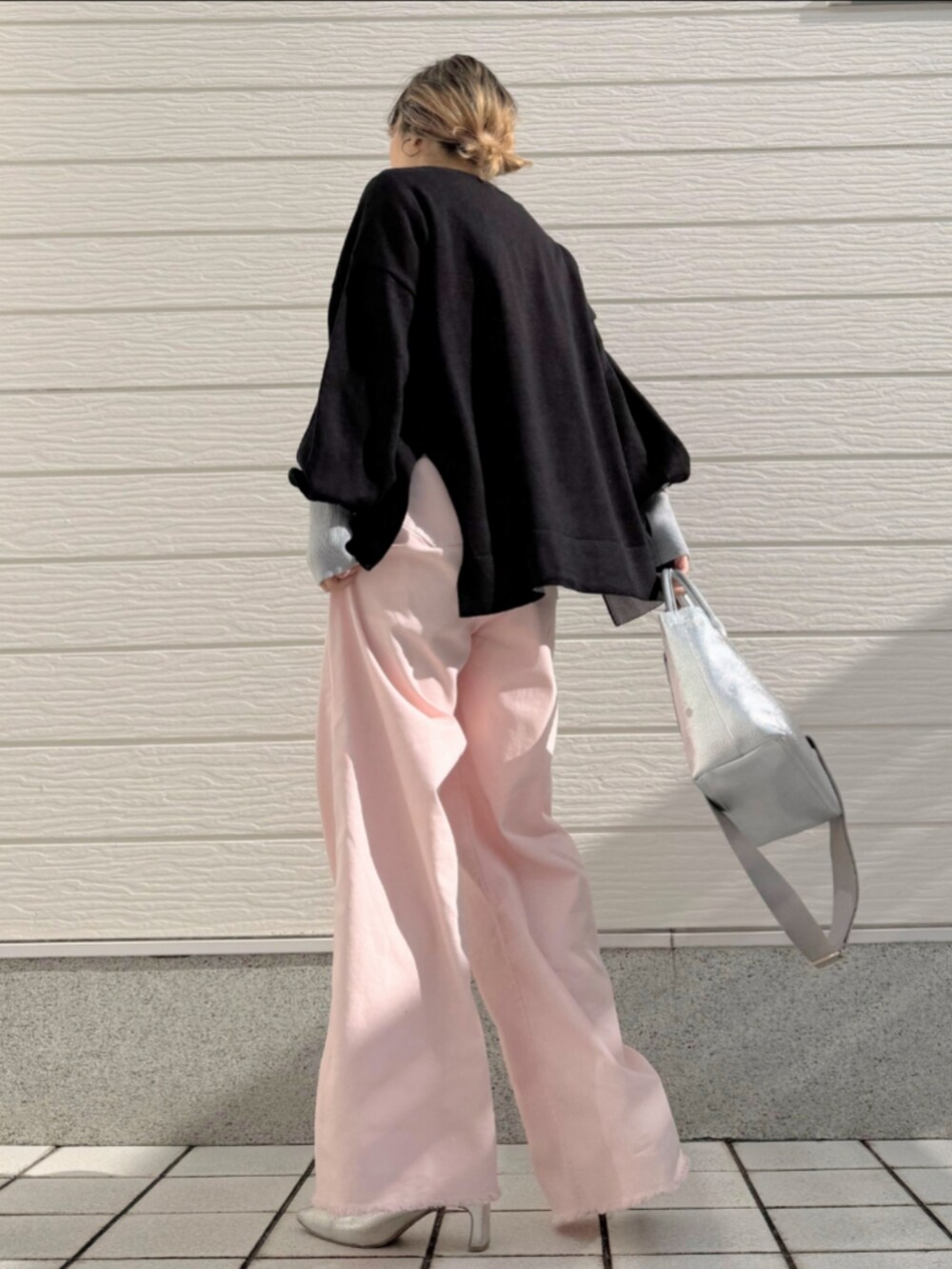 シルバー系のトートバッグ、ピンク系のデニムパンツ、ブラック系のニット/セーターを着用したレディースの冬コーディネートの3枚目の写真