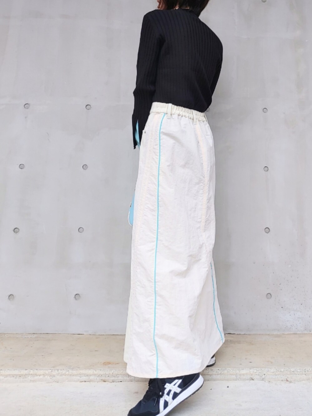 ブルー系のトートバッグ、ホワイト系のデニムスカート、ブラック系のスニーカーを着用したレディースの冬コーディネートの3枚目の写真