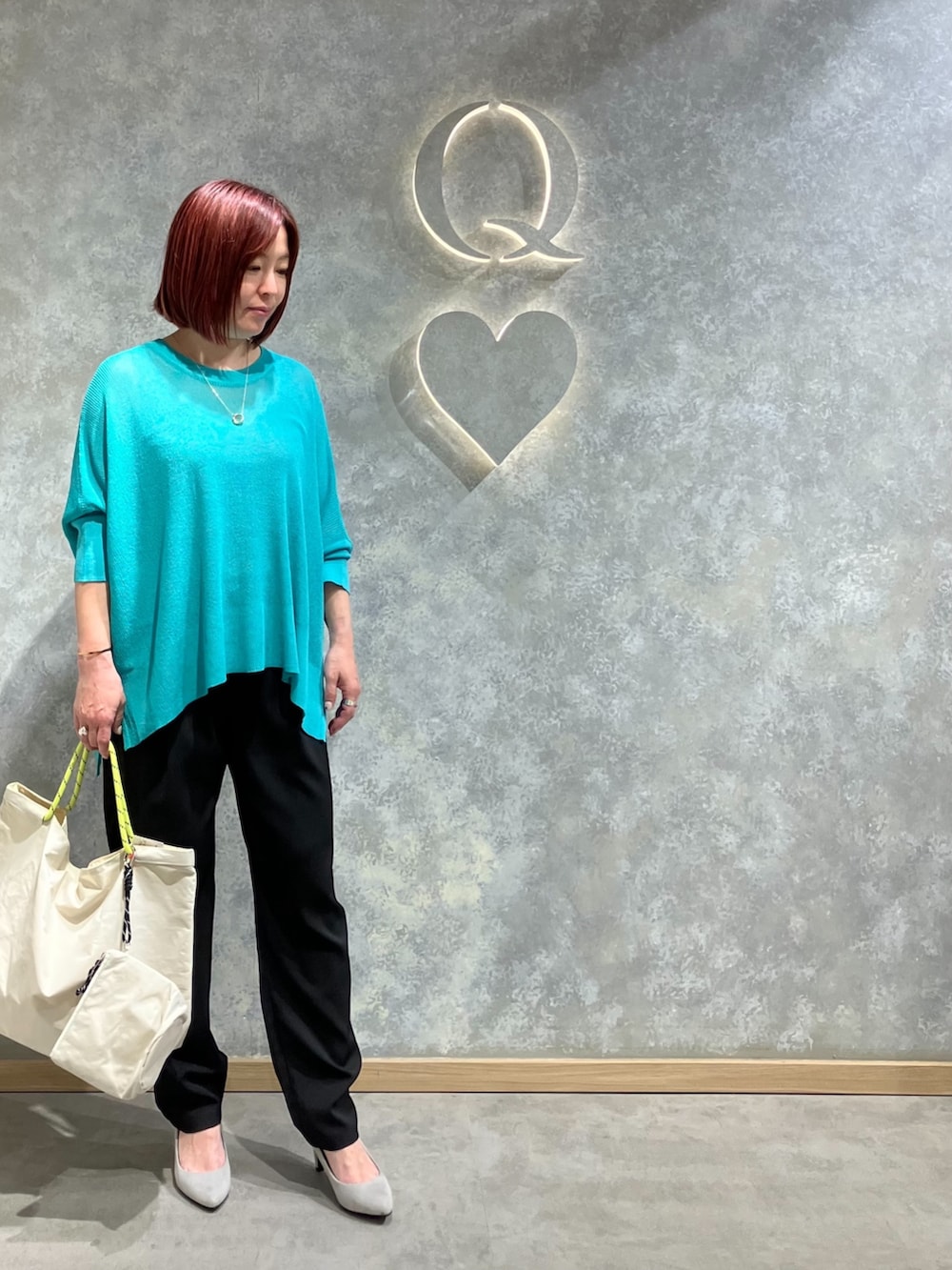 グリーン系のニット/セーター、ブラック系のその他パンツ、ホワイト系のトートバッグを着用したレディースの春コーディネートの3枚目の写真