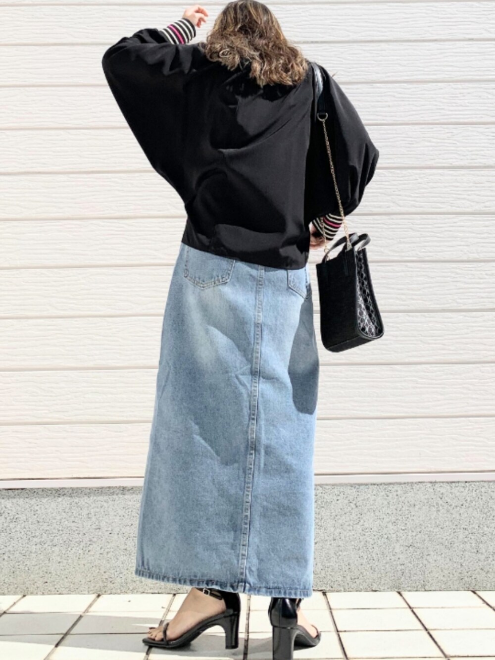ブルー系のデニムスカート、ブラック系のシャツ/ブラウス、ブラック系のショルダーバッグを着用したレディースの春コーディネートの4枚目の写真