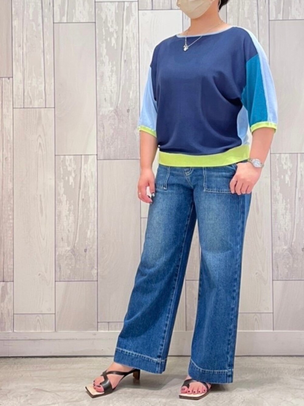 グリーン系のトートバッグ、ブルー系のデニムパンツ、ブラック系のサンダルを着用したレディースの夏コーディネートの2枚目の写真